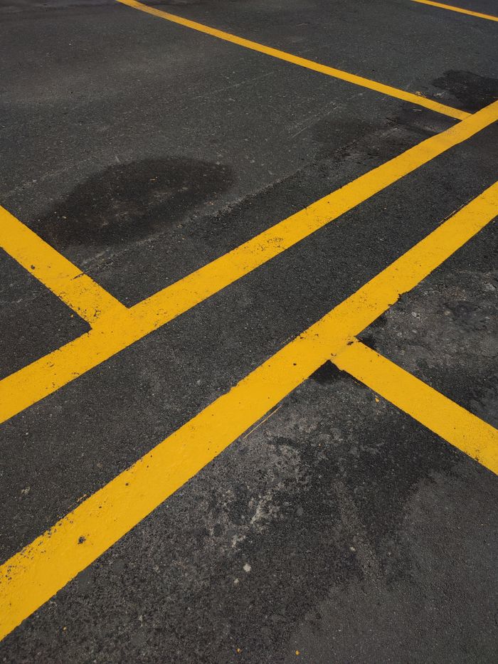 Close-up of bright yellow lines marking a parking area on dark asphalt pavement.