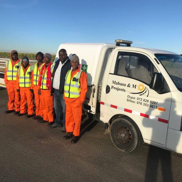 Mabaso and M Projects team standing beside a branded company vehicle