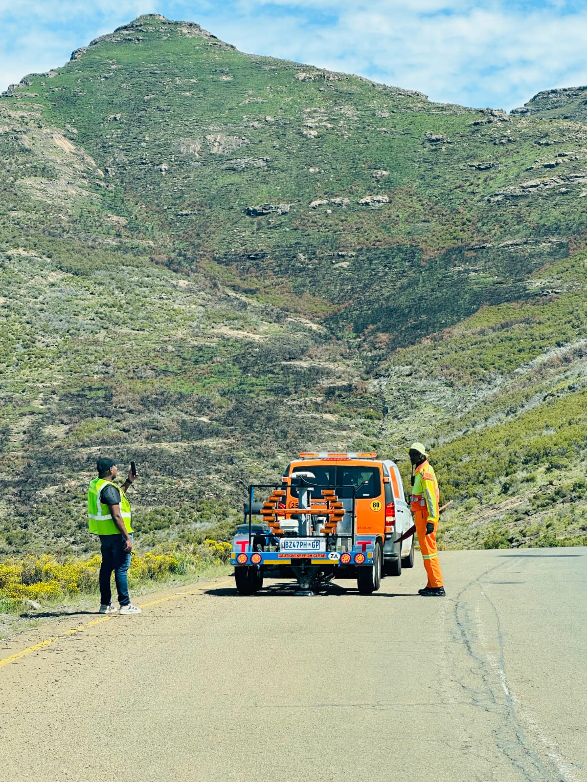 Team members with a line-marking vehicle on a scenic pass